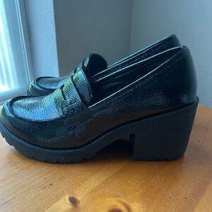 Black chunky loafers with a slight heel. Textured patent leather